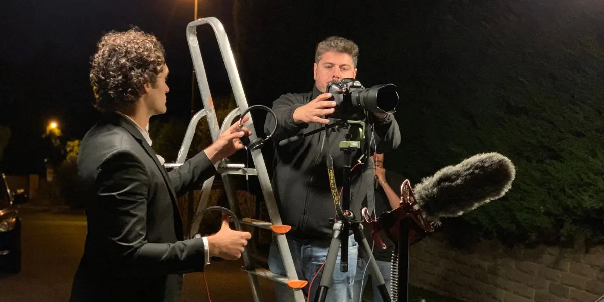 Riprese notturne: un fotografo su una scala e il microfono in asta sul set