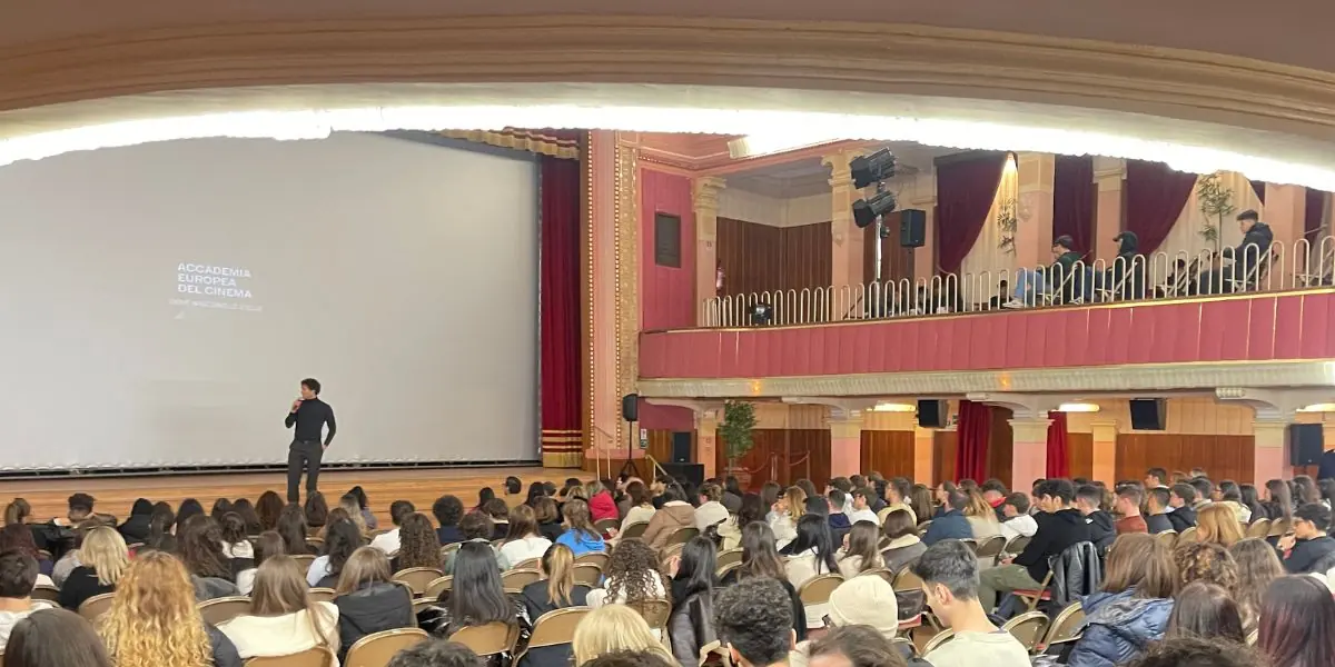 Una figura sul palco di un teatro davanti alla platea gremita